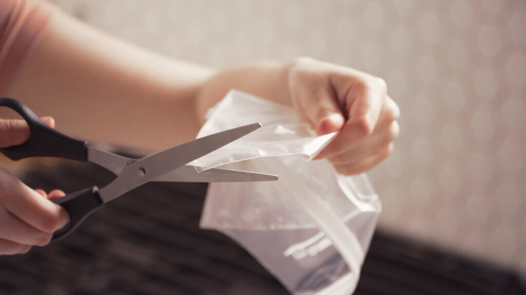 Woman holding zip top bag, cutting a corner off with scissors so she can use as a pastry bag