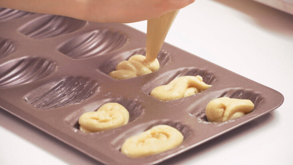 Piping cookie batter into baking molds