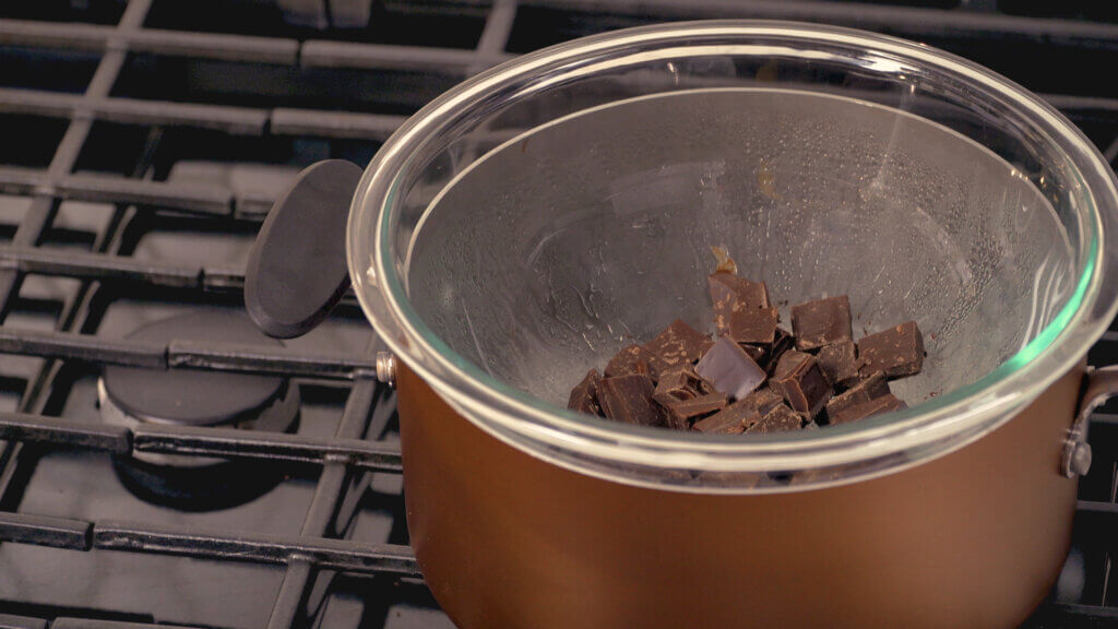Double boiler on stove, melting chocolate chunks by using a tempering chocolate method