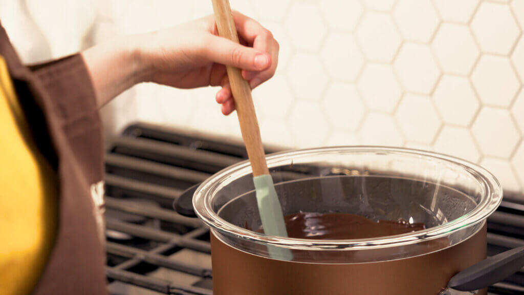 Tempering chocolate by stirring chocolate in a double boiler