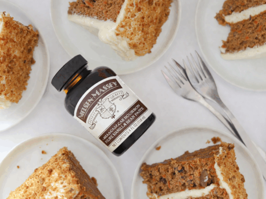 Slices of carrot cake plated with a jar of vanilla bean paste sitting nearby