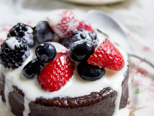 mocha cake on a plate with berries and drizzled creme
